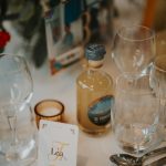 Une table élégamment dressée avec une bouteille artisanale de punch "Ti Tonton", mise en valeur au centre d’un décor floral raffiné.